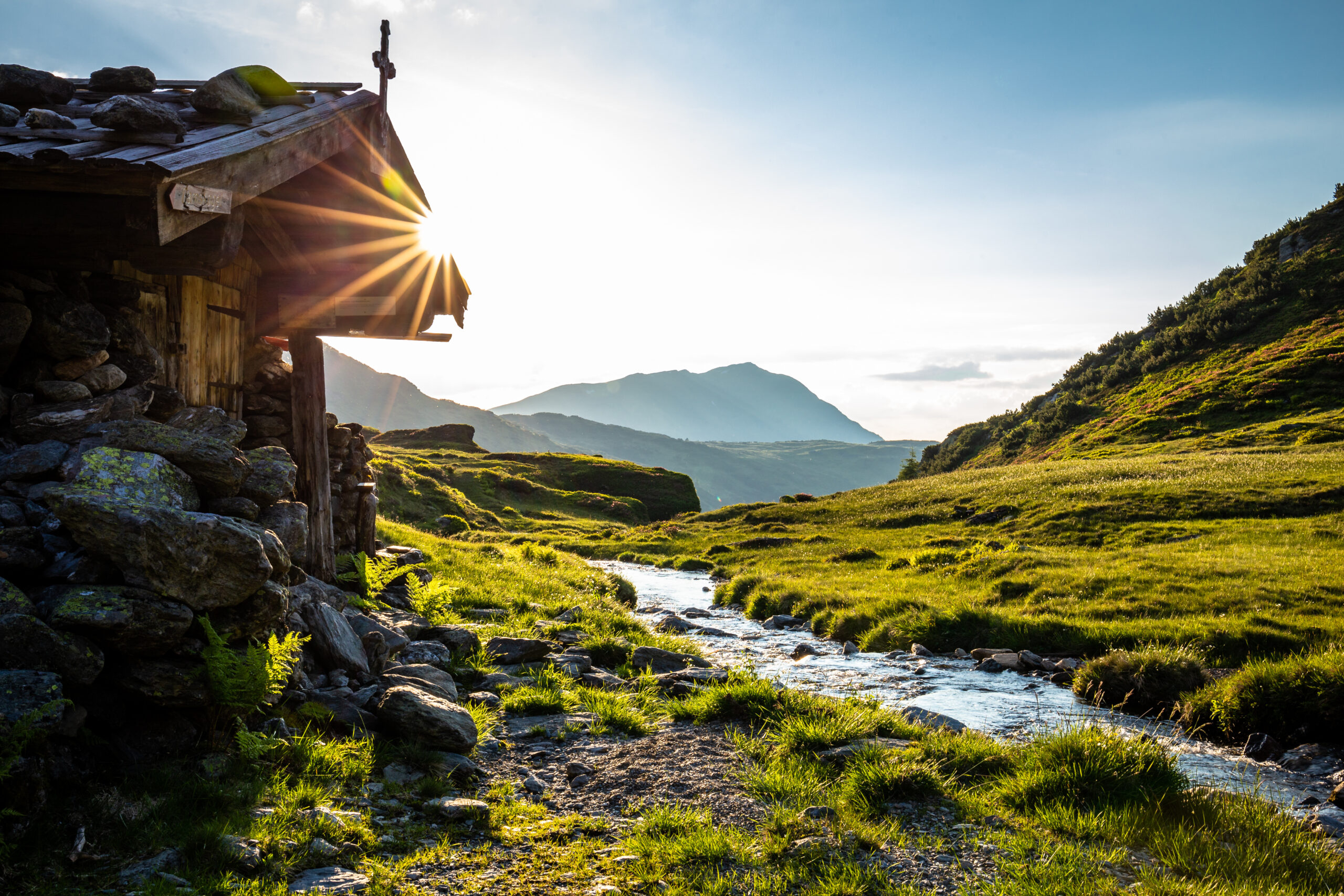 Alm neben einem Bach im Sommer beim Sonnenuntergang